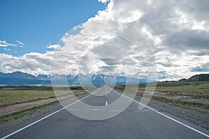 Long asphalt road. Mountains in the horizon.