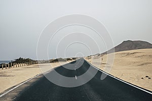 Long asphalt road qith sand desert around. Concept of car travel and adventure