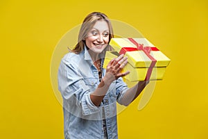 Long awaited present. Portrait of curious woman looking inside gift box. studio shot  on yellow background photo
