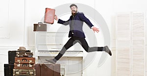 Long awaited vacation concept. Macho attractive, elegant on cheerful face carries vintage suitcases, jumping. Man with photo