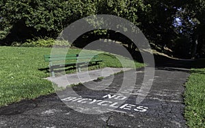 Long bench in sunny days with signs no bicycles on road