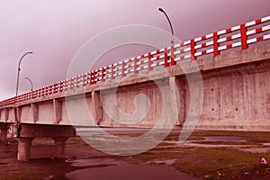 Long Big concrete bridge.An elevated concrete highway spanning across a Dark cloudy sky.view under the grey briage in the city. photo