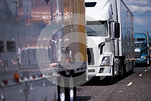 Long big rigs semi trucks and trailer convoy on the road