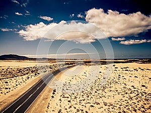 Long black asphalt road in the middle of the desert with nature and outdoors around - concept of travel and adventure in