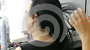 Long black hair of a young woman blow-dry in a hairdressing salon