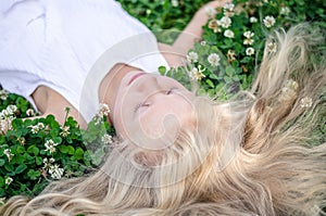 Long blond healthy hair of beautiful girl lying in grass