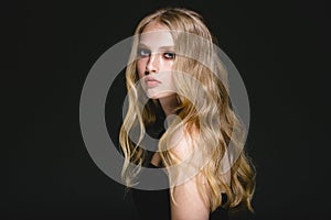 Long blonde hair model woman over black background film effect.