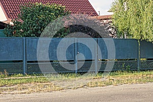 Long blue metal fence wall with a closed iron door