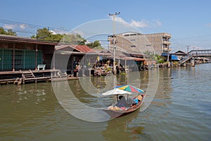 Long boat is floating on river around wooden thai old house