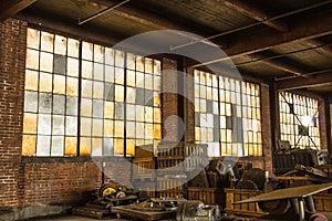 Long brick wall with frosted windows of an abandoned factory with debris left on the floor