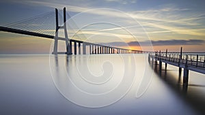 Largo tiempo puente a través de un rio en Lisboa sobre el amanecer 