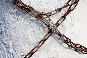 A long chain made of metal is covered with a little rust wrapped around the concrete wall and prohibits any movement. photo