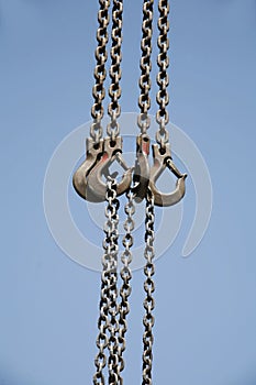 Long chains with hooks hanging vertically against blue sky