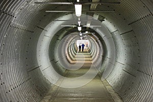 A long circular pedestiran tunnel sheeted in corrugated metal