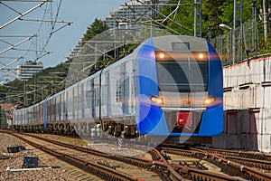 Long composition of a blue suburban electric train on the hauls of the route
