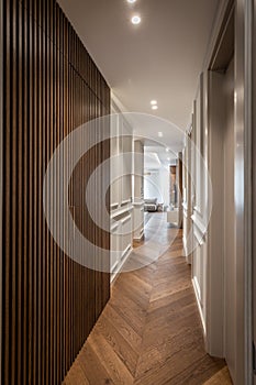 Long corridor with brown wooden wall and parquet floor