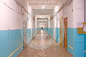 A long corridor with doors to offices. Marble floors. Old industrial building.