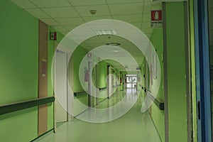 The long corridor of the hospital with doors, and rooms with medical equipment and hospital furniture.