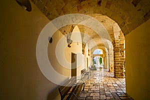 A long, covered and arched portico hallway in the historic center of Brindisi, Italy