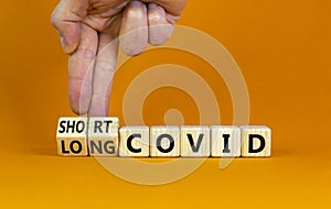 Long covid symbol. Doctor turnes wooden cubes and changes words `short covid` to `long covid`. Beautiful orange background, co