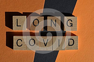 Long Covid, words in wooden alphabet letters isolated on orange and black background