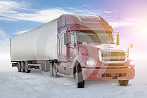 Long-distance bonnet truck with a white semitrailer on bright background with sky