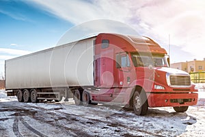 Long-distance bonnet truck with a white semitrailer in the countryside at winter
