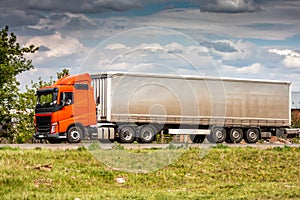 Long-distance truck with a semitrailer moves in the countryside