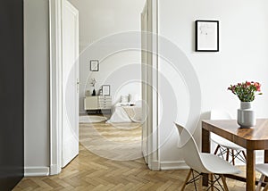 A long distance view from a dining room into a bedroom in a high ceiling flat. Monochromatic white interior with herringbone parqu