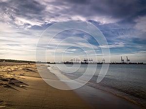 Long empty clean sand Stogi beach in Gdansk, Poland with Stalin shipyard with cranes in the background