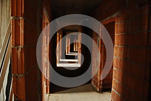 Long empty corridor between brick walls