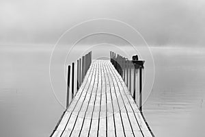 long empty wood fishing dock on a foggy summer morning at the lake