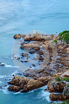 Long exposure with blurred water of a lighthouse on a rock at the entrance to the Knysna lagoon