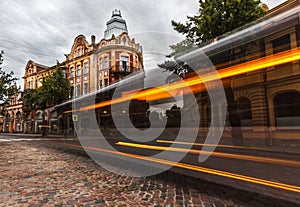 Long-exposure of bus with historical building.