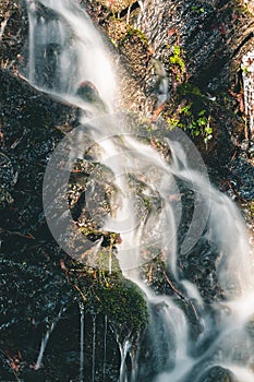 Long exposure creamy waterfall on small forest brook from thawing snow shined by sunset sun. Czech republic