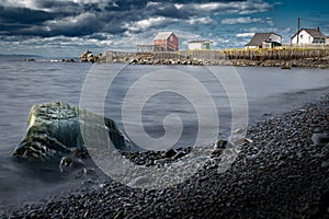 Long exposure East coast scene of distant Atlantic traditional homes in a calm bay at Bonavista Newfoundland Canada