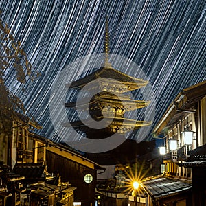 A long exposure evening street view of the Yasaka padoda illuminated by the ground and star trails