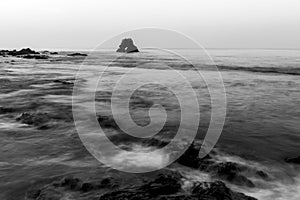 Long exposure fluffy ocean mists rush over tidal pool rocks at the beach