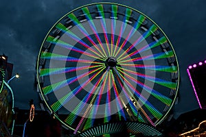Long exposure of a giant wheel in motion with colorful lights at a christmas fair against a cloudy night sky, abstract image
