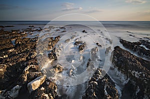 Long exposure landscape rocky shoreline at sunset