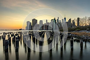 Long exposure of the Lower Manhattan skyline at sunset with an old Brooklyn pier in the foreground