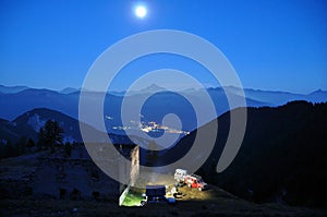Long exposure night photo of an off road campsite in the mountains with old ruin and a stunning view of the Alp mountain tops and