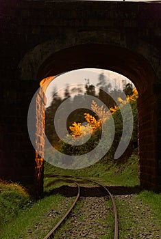 A long exposure night photograph of railways tracks passing through on old arched stone built tunnel, Ooty, India.