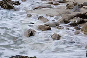 Long exposure Pacific seascape waves on the rocky stoney shore. Slow shutter speed used to see the movement Soft focus shot