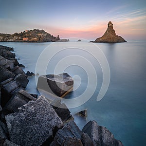Long exposure panoramic shot of the Cyclope Island with breakwater cube blocks at the coast of Acitrezza, Sicily, Italy photo