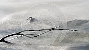 Long exposure photo - water flowing over rock and drifted tree branch, everything smooth, only stationary rock is in focus