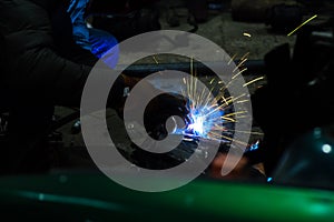 long exposure photo welder performs welding works of metal structures for custom cars
