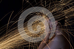 Long exposure photo of woman blocking glowing sparks artistic co