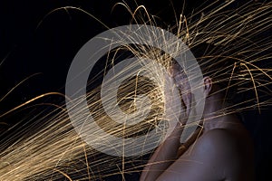 Long exposure photo of woman blocking glowing sparks artistic co