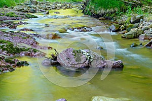 Long exposure picture of a stream flowing with rocks and natural light